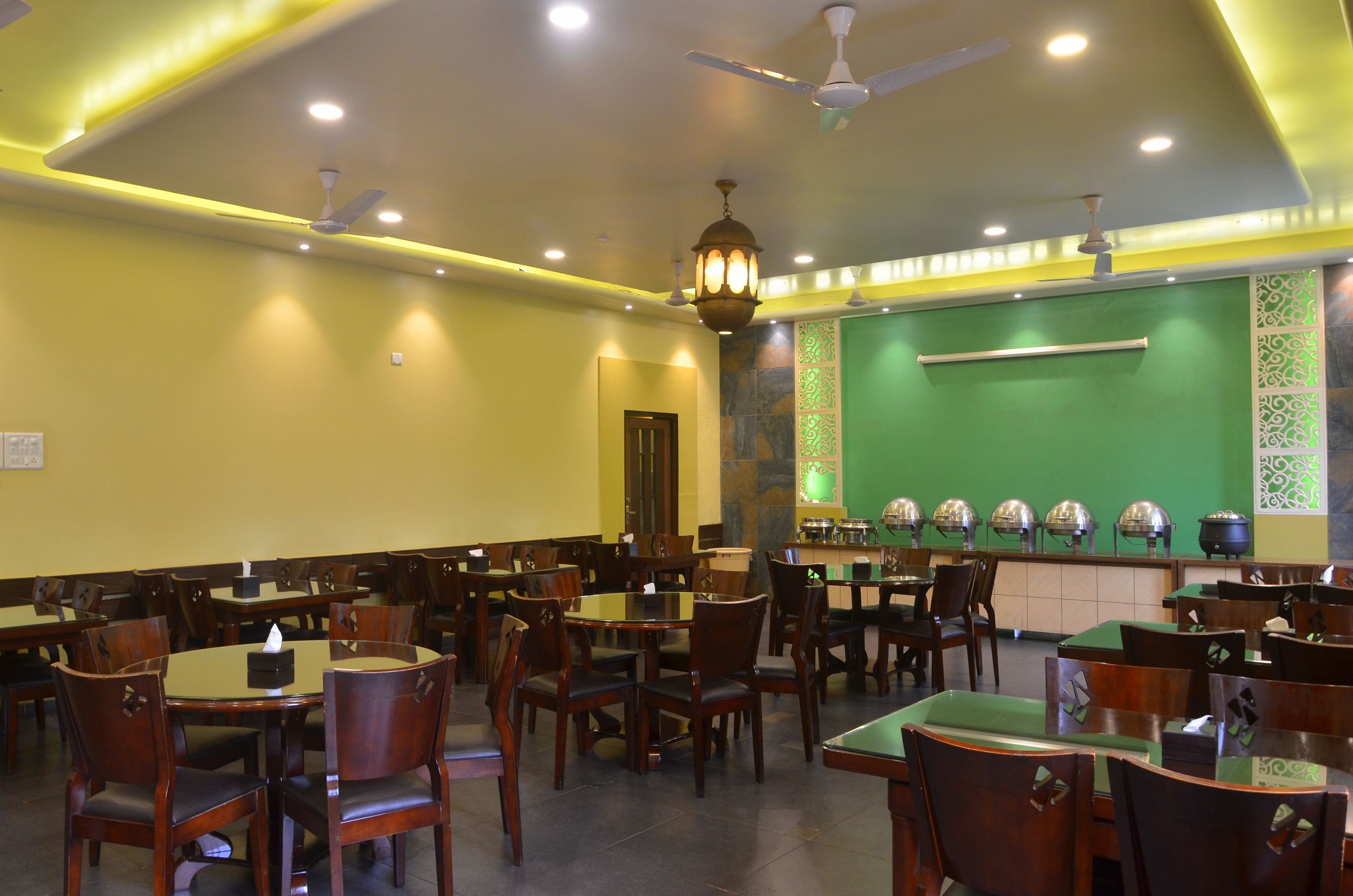 A restaurant with multiple tables and chairs, ceiling fans, and decorative lighting.