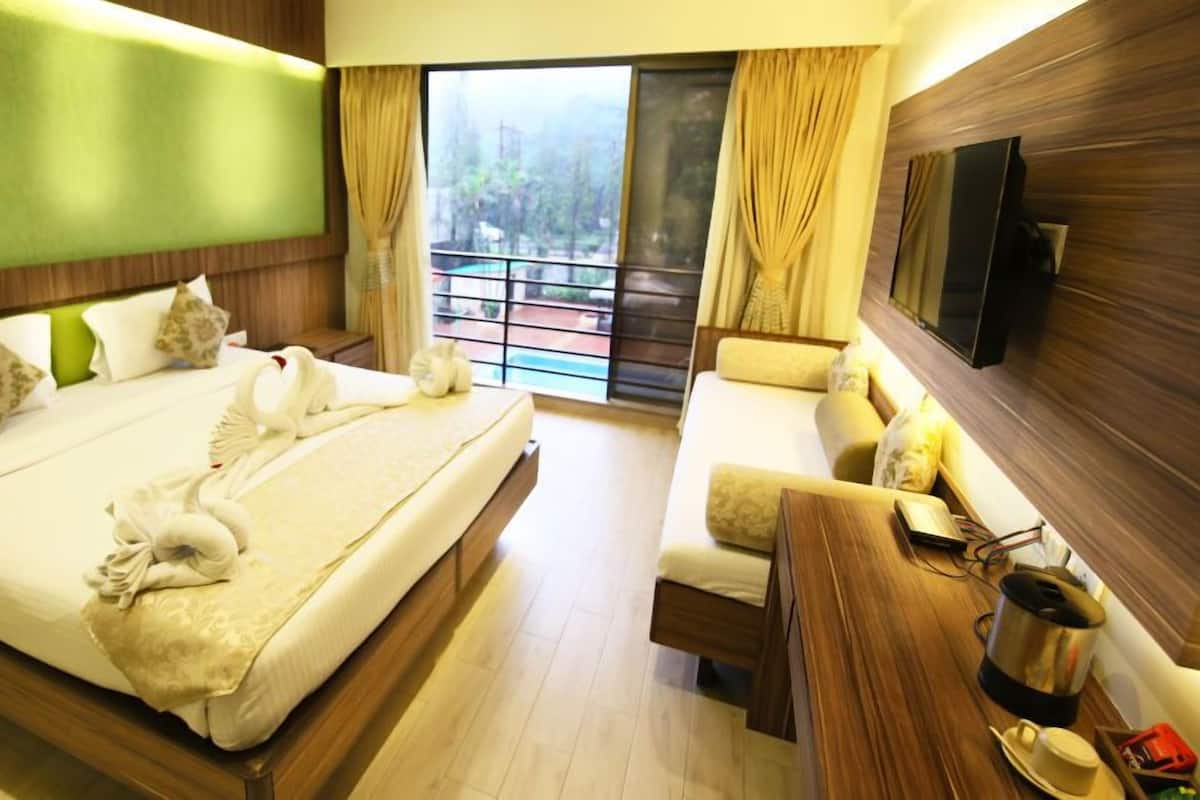 Ein Hotelzimmer mit einem großen Bett, einer Couch, einem Fernseher und einem Balkon mit Blick.