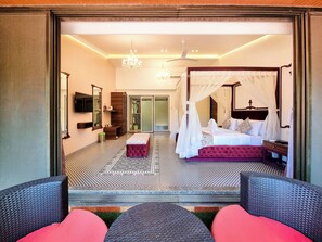 Une chambre spacieuse avec un lit à baldaquin, un grand miroir et une télévision.