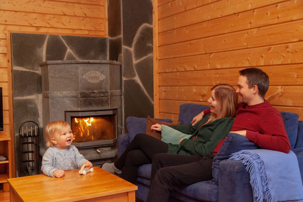 A cozy living room with a stone fireplace, wooden walls, and a blue sofa.