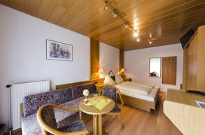 A modern hotel room with a wooden ceiling, a bed, a sofa, a small table with a vase, and a painting on the wall. - Landhotel Hamburger Hof (Söhlde)