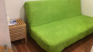 A green sofa with a wooden side table beside it. - Hanzhong House (Taipei)