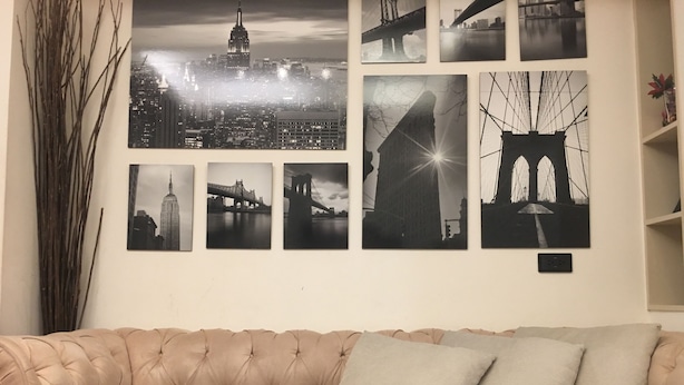 A beige tufted sofa with two cushions against a wall with multiple black and white photographs of bridges and buildings. - Hanzhong House (Taipei)