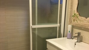 A bathroom with a glass shower enclosure, a white sink, and a toilet. - Hanzhong House (Taipei)