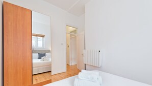 Une chambre d’hôtel moderne avec une armoire en bois, un lit soigneusement fait et un radiateur blanc.