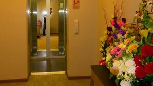An elevator with a mirror, a wall-mounted air conditioner, and a floral arrangement on a table. - Prince 33 Hotel (Johor Bahru)