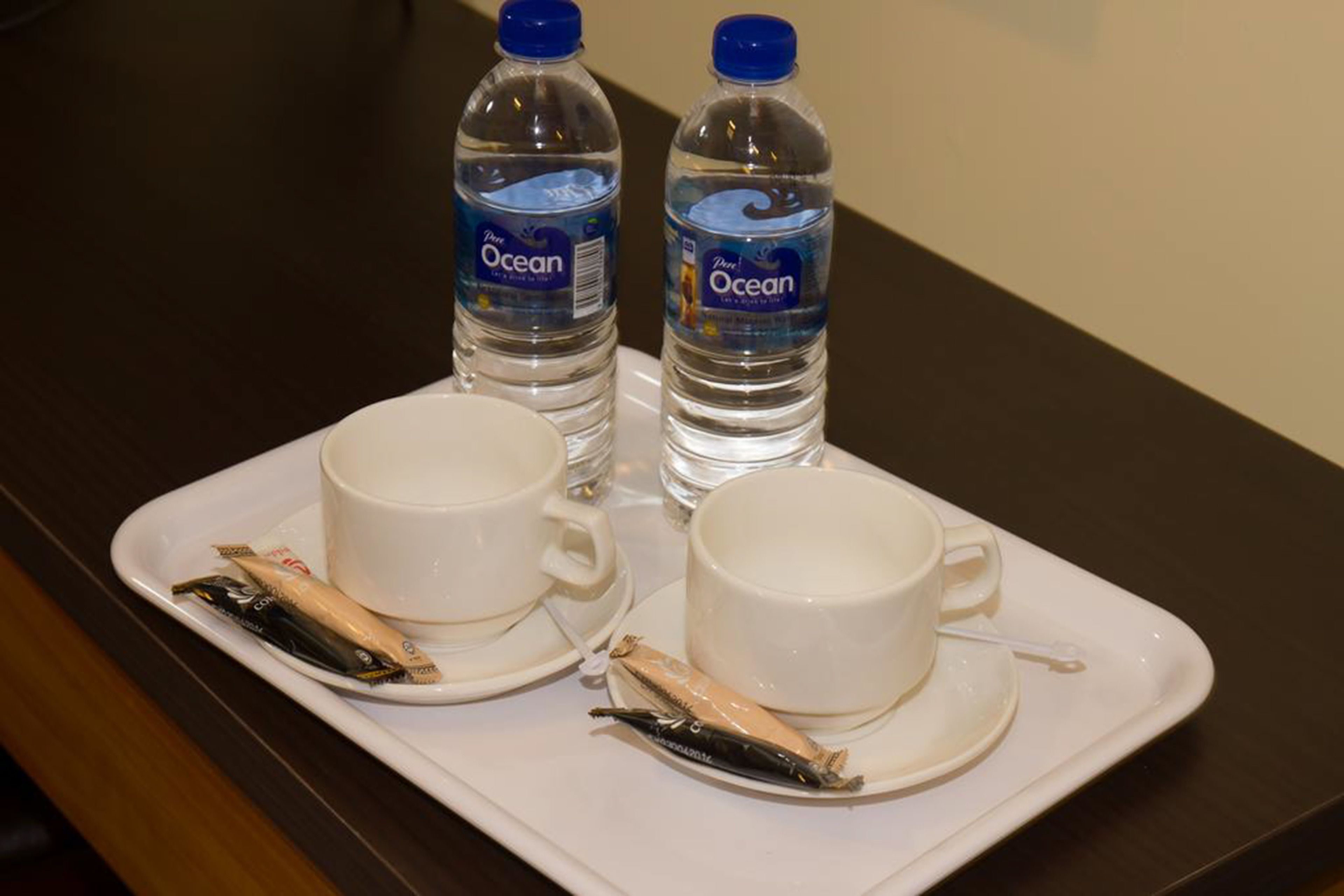 A tray with two cups, two bottles of water, and two packets of snacks.
