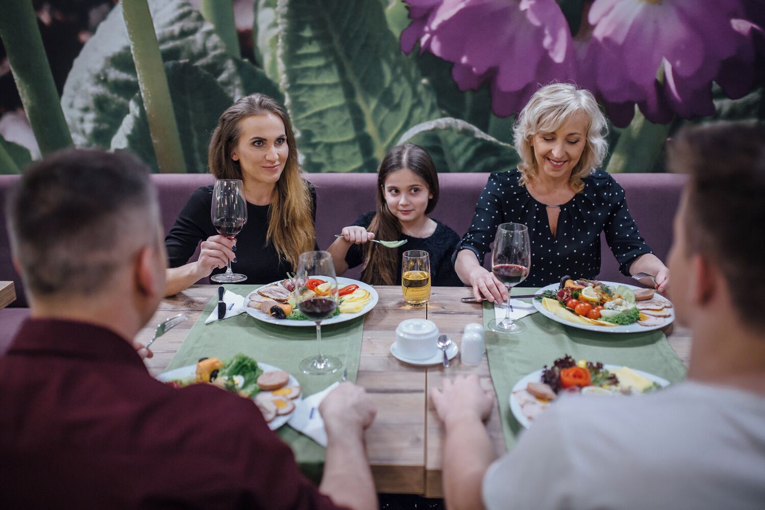 A group of people dining at a table with various dishes and drinks.