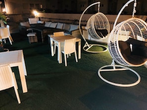 An outdoor seating area with a table, chairs, and hanging chairs. - B&B Stellamarina (Pulsano)