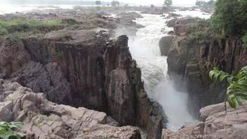 A natural landscape with a waterfall cascading down a rocky gorge.