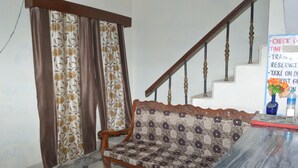 Ein Zimmer mit einer gepolsterten Couch, einer Holztreppe und einem Schild mit Informationen zur Anreise.