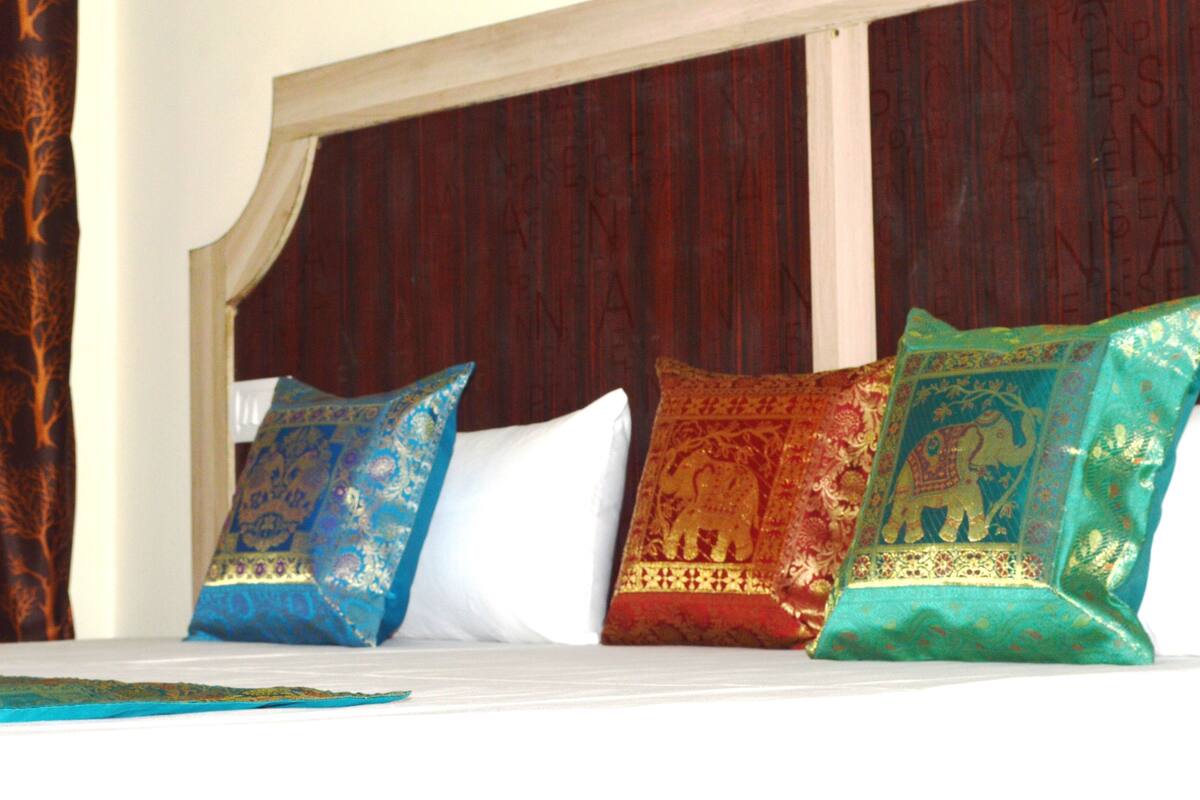 Un lit avec trois coussins décoratifs et une tête de lit en bois.