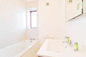 A bathroom with a bathtub, a sink, and a window.