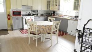 A kitchen with white cabinets, a microwave, stove, and a dining table with chairs. - Keep Cool Apartment (Gros Islet)
