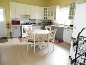 A kitchen with white cabinets, a microwave, stove, and a dining table with chairs. - Keep Cool Apartment (Gros Islet)