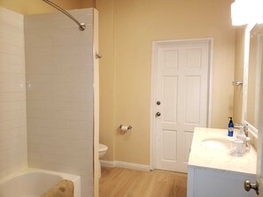 A bathroom with a bathtub, a shower, a toilet, and a sink with toiletries. - Keep Cool Apartment (Gros Islet)