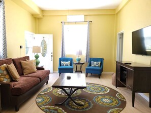 A living room with a brown sofa, two blue armchairs, a coffee table, and a TV on a stand. - Keep Cool Apartment (Gros Islet)