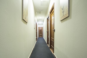 Un couloir étroit, avec des portes de chaque côté, chacune étant marquée d’un numéro.