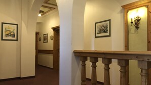 A hallway with wooden railings, framed artwork on the walls, and a wooden door at the end. - Gästehaus Maria (Garmisch-Partenkirchen)