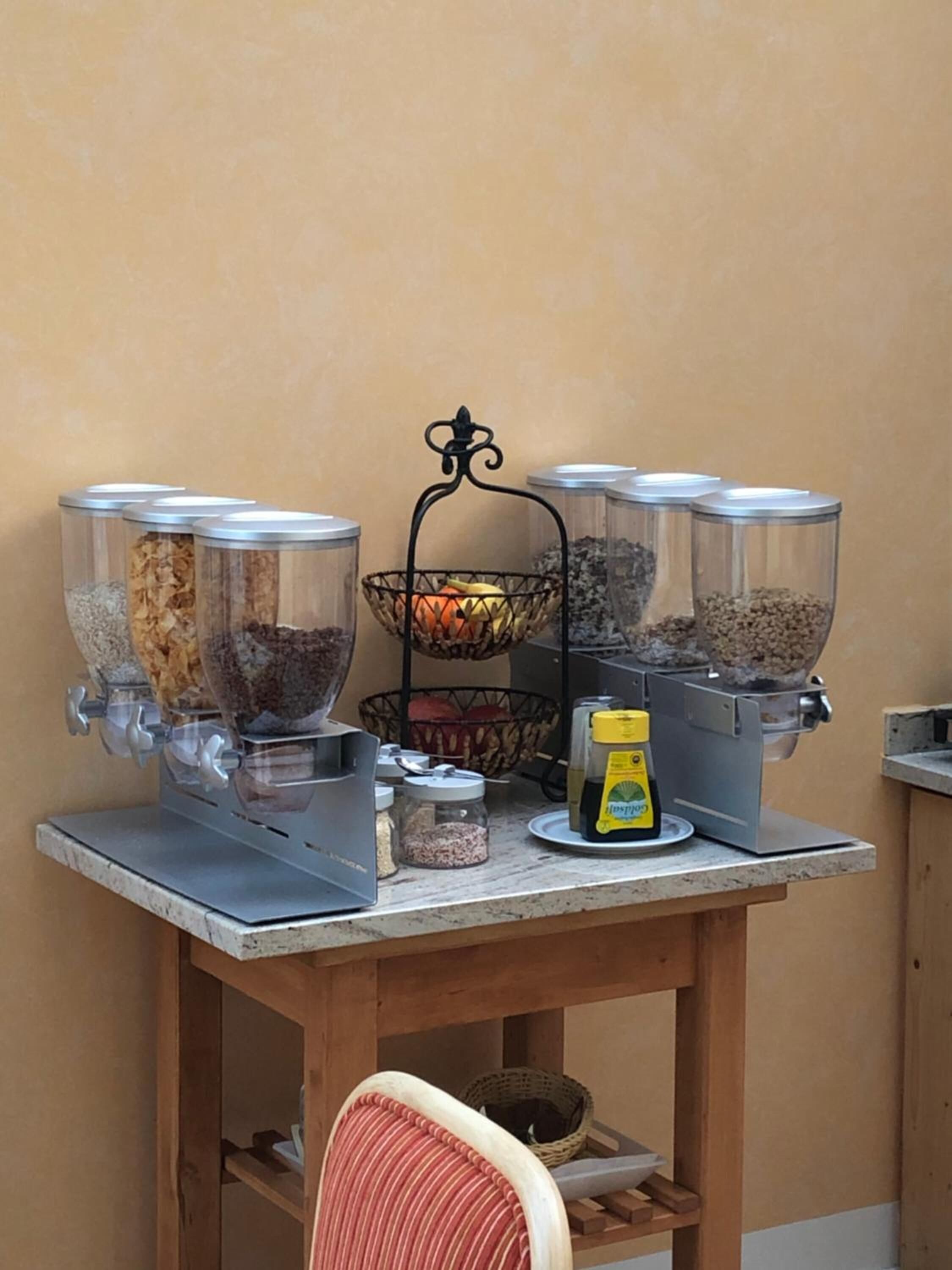 A kitchen counter with four food processors, a basket of fruits, and a bottle of cooking oil.