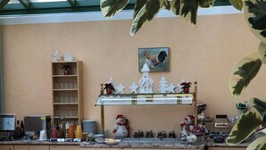 A kitchen with wooden cabinets, a glass-top counter, and a dining area with a table and chairs. - Gästehaus Maria (Garmisch-Partenkirchen)