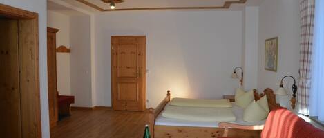 A cozy room with a wooden bed, a small table with a bottle, and a red sofa.