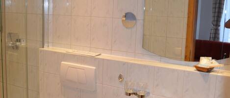 A bathroom with a toilet, sink, and glass shower enclosure.