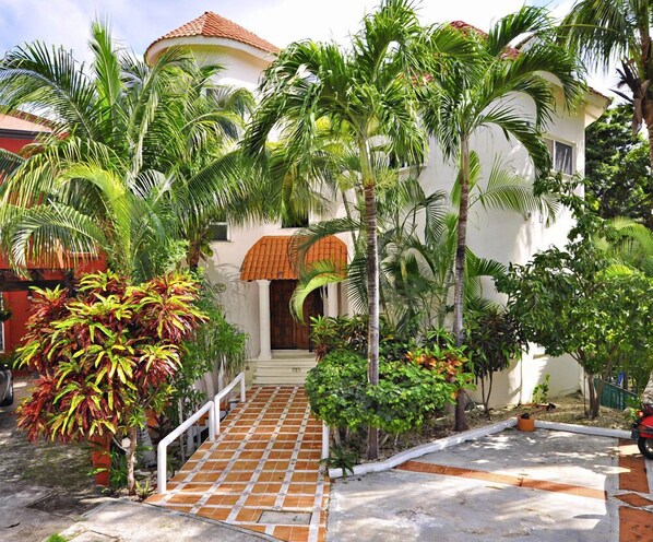 A white building with a tiled entrance and a red-tiled roof.