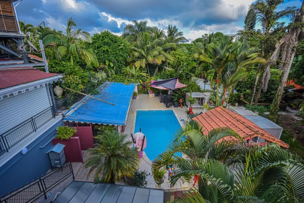 Un quartier résidentiel doté d’une piscine, entourée d’une végétation luxuriante et de palmiers.
