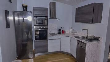 Eine moderne Küche mit Edelstahlgeräten, einer Mikrowelle, einem Backofen und einem Geschirrspüler.
