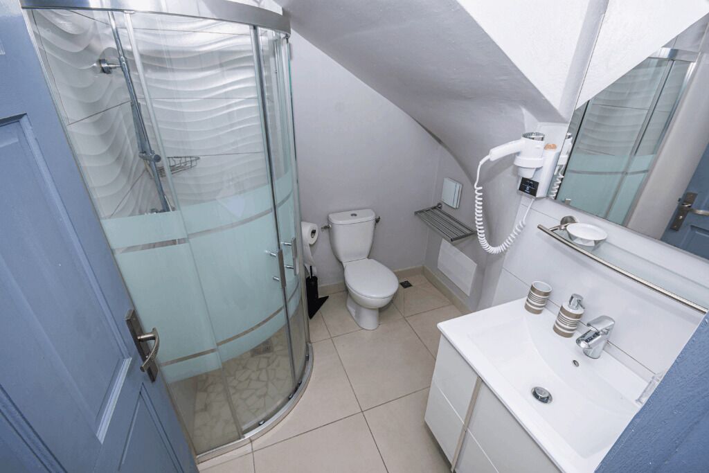 A modern bathroom with a glass shower enclosure, a toilet, a sink with a mirror, and a towel rack.