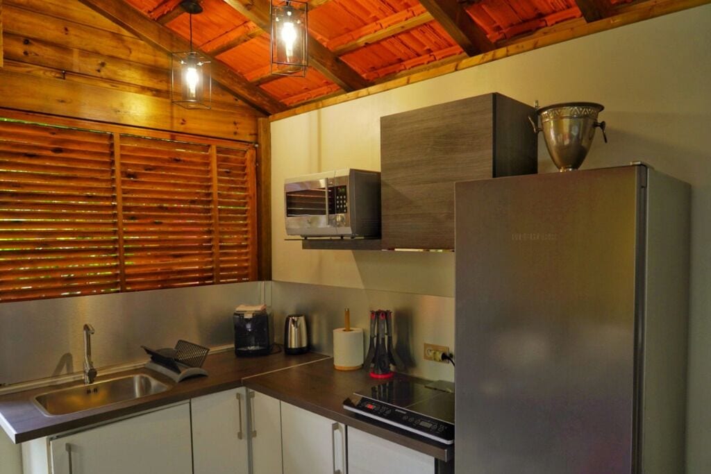Una cucina moderna con frigorifero in acciaio inox, forno a microonde e macchina del caffè.