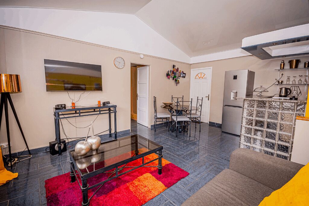 A modern living room with a glass coffee table, a sofa, and a dining area with a table and chairs.