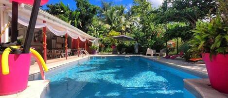 Una piscina al aire libre, sombrillas, sillones reclinables de piscina