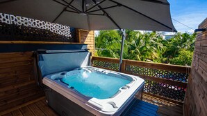 A hot tub on a wooden deck with a wooden fence and palm trees in the background. - Redoute Paradise (Fort-de-France)