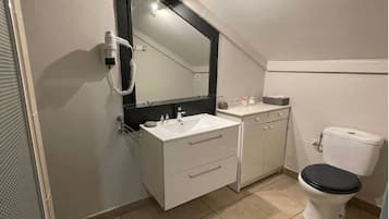Un baño pequeño y moderno con un lavamanos blanco, un inodoro negro y un espejo grande sobre el lavamanos.