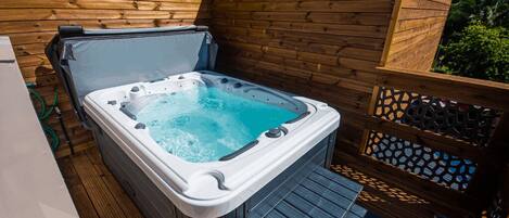 A hot tub on a wooden deck with a wooden fence and lattice design.