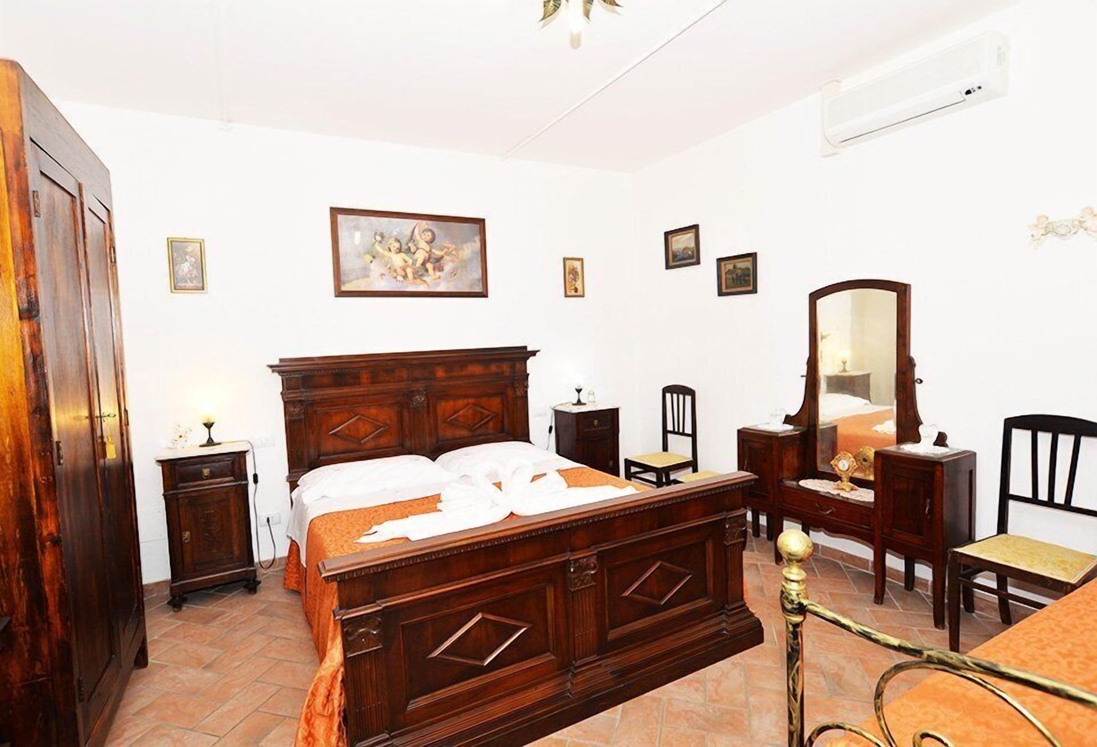 A traditional bedroom with a wooden bed, a dresser, a mirror, and a chair.