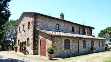 A stone building with a tiled roof, multiple windows, and a large wooden door.