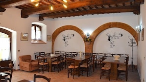 A dining area with multiple tables and chairs, wooden beams on the ceiling, and decorative wall arches.