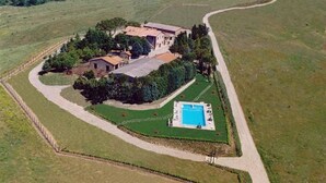 An aerial view of a property with a swimming pool, surrounded by well-maintained lawns and a winding path.
