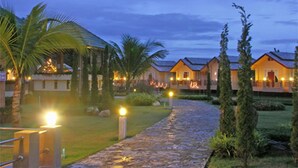 A pathway leading to a row of well-lit, single-story buildings with a tropical garden setting. - Maerim Whale Park Resort (Mae Rim)