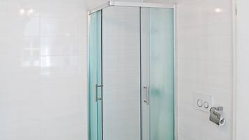 A modern bathroom with a glass shower enclosure, a white toilet, and a light fixture above the shower.