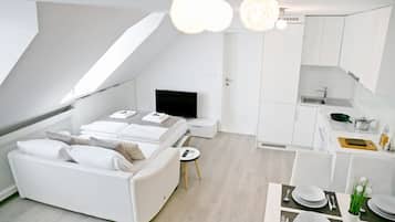 Een modern appartement met een wit thema, een leefruimte in loftstijl, een kitchenette en een eethoek.
