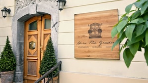 A wooden door with a sign above it, a small potted plant, and a wooden plaque on the wall. - Apartments Hiša Pod Gradom (Ljubljana)