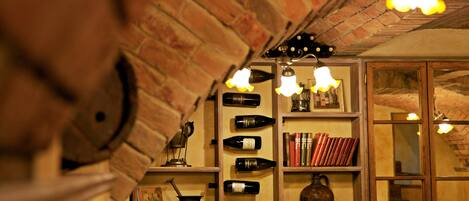 Une pièce avec un mur en briques, des étagères remplies de bouteilles de vin, de livres et un vase.