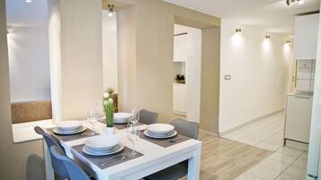 A modern dining area with a white table set for four, including plates, glasses, and cutlery.
