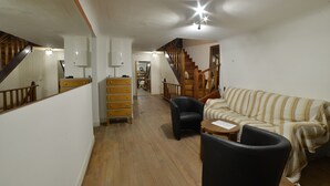 A spacious living area with a wooden staircase, a sofa, a coffee table, and a wooden dresser. - Etxe Arrosa (Saint-Martin-d'Arrossa)