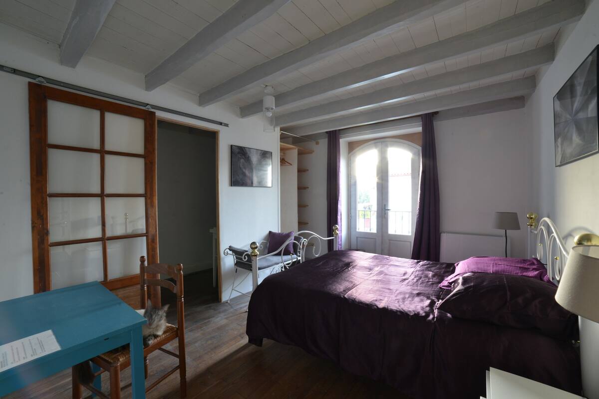 A bedroom with a bed, a desk, and a chair.
