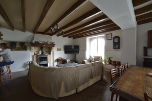 A cozy living room with a sofa, wooden dining table, and a television. - Etxe Arrosa (Saint-Martin-d'Arrossa)